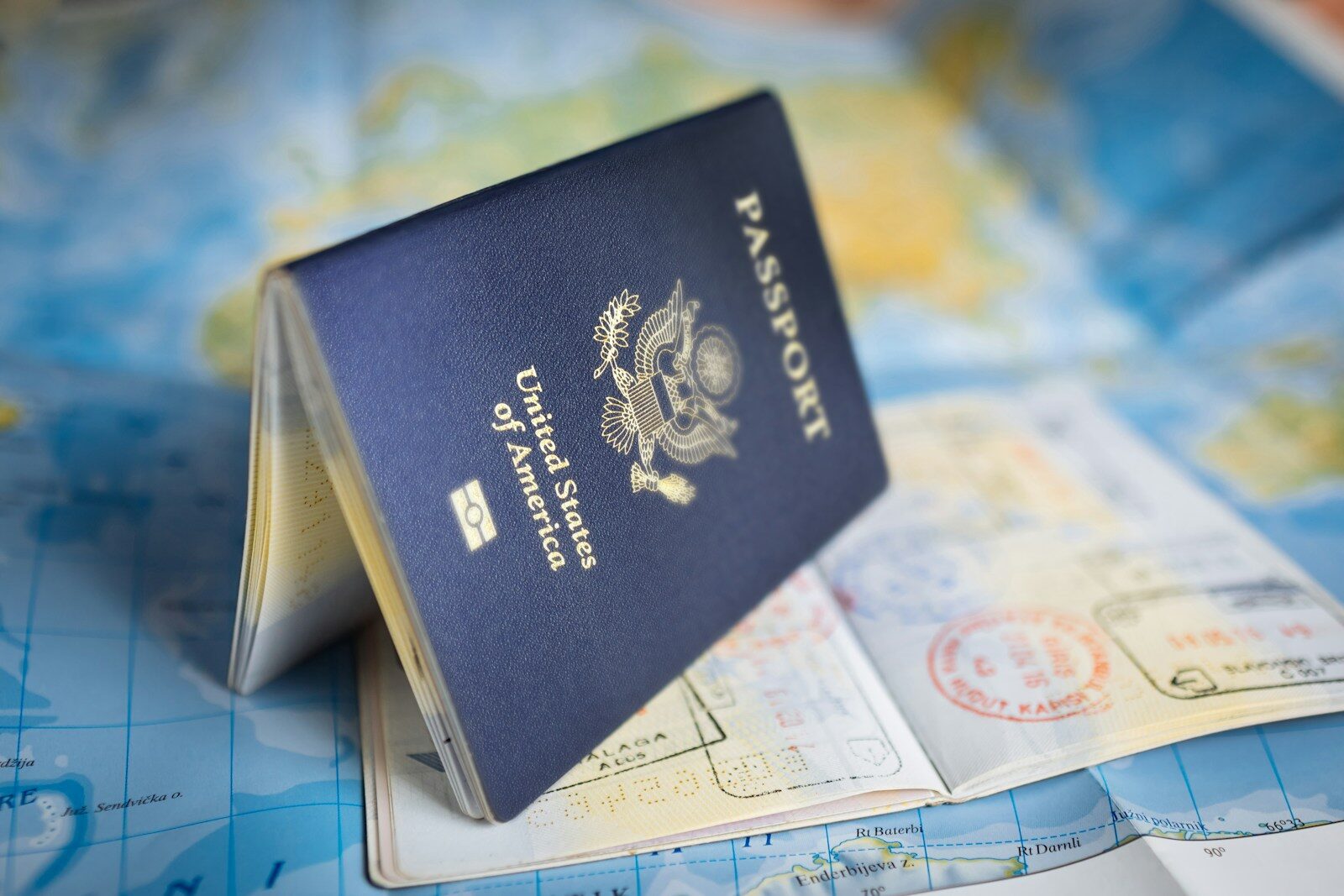 Do You Need a Passport for a Cruise from Norfolk? (2026 Guide) 1 US passport book standing on a world map with travel stamps